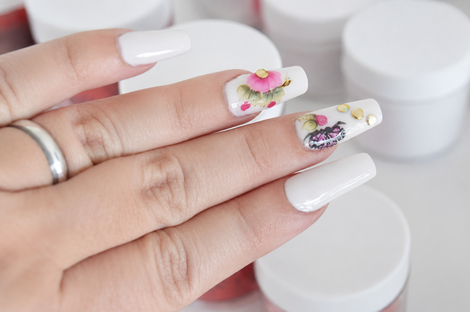 Unhas brancas com detalhes florais feitas na esmalteria do salão